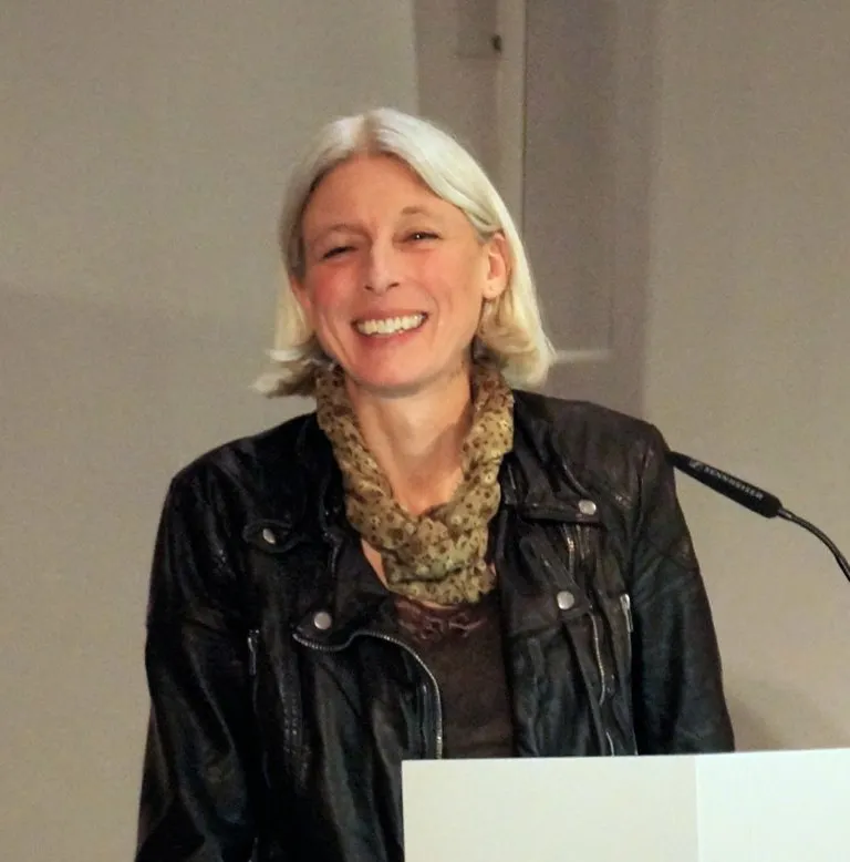 Photo of Dagmar Herzog, smiling at a lectern.