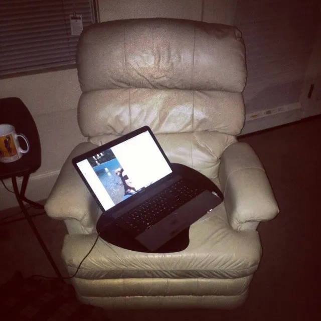 A laptop open on a cream leather recliner at night