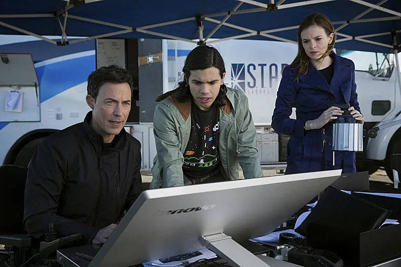 Barry’s mentors at S.T.A.R. Labs, Harrison Wells, Cisco Ramon and Caitlin Snow, watching a monitor in the field.